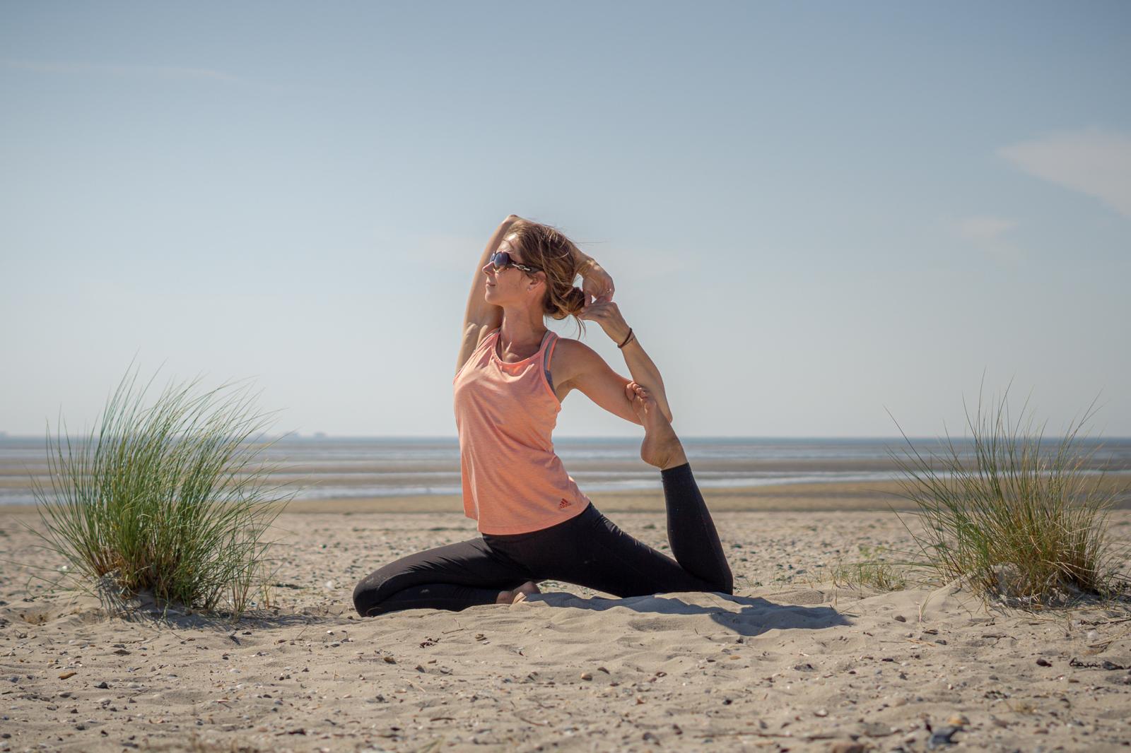 Sabine Eiswirth in der Königs-Taubenpose zwischen Strandgräsern