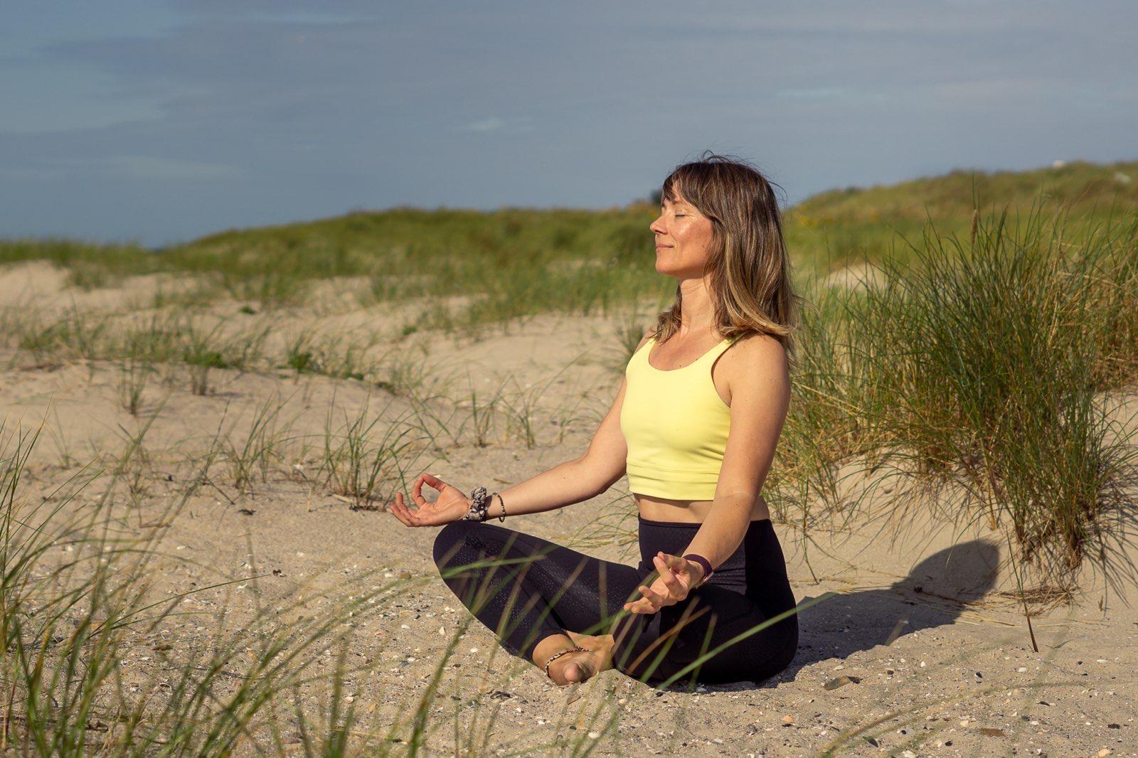 Sabine Eiswirth im Schneidersitz meditierend in den Dünen – Seis Yoga