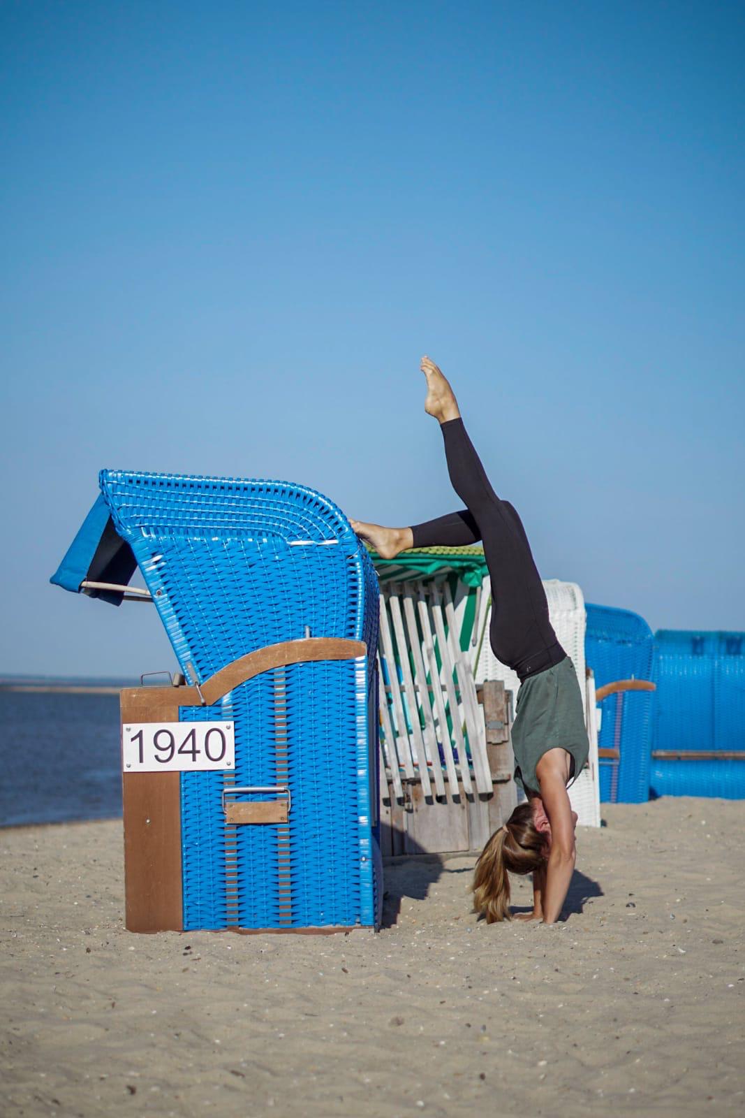 Sabine Eiswirth in verspielter Kopfstand-Pose am Strand – Freude und Leichtigkeit bei Seis Yoga